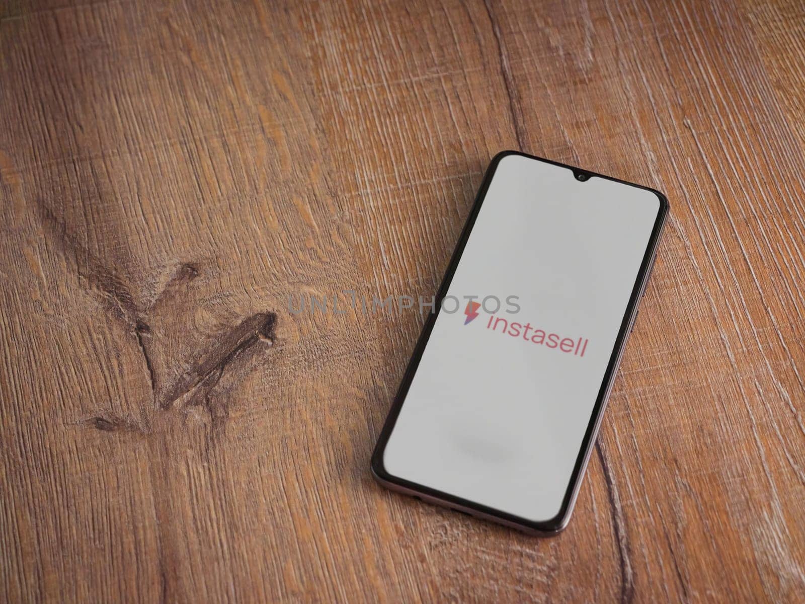 Lod, Israel - July 16,2023: Instasell app launch screen on smartphone on wooden background. Top view flat lay with copy space.