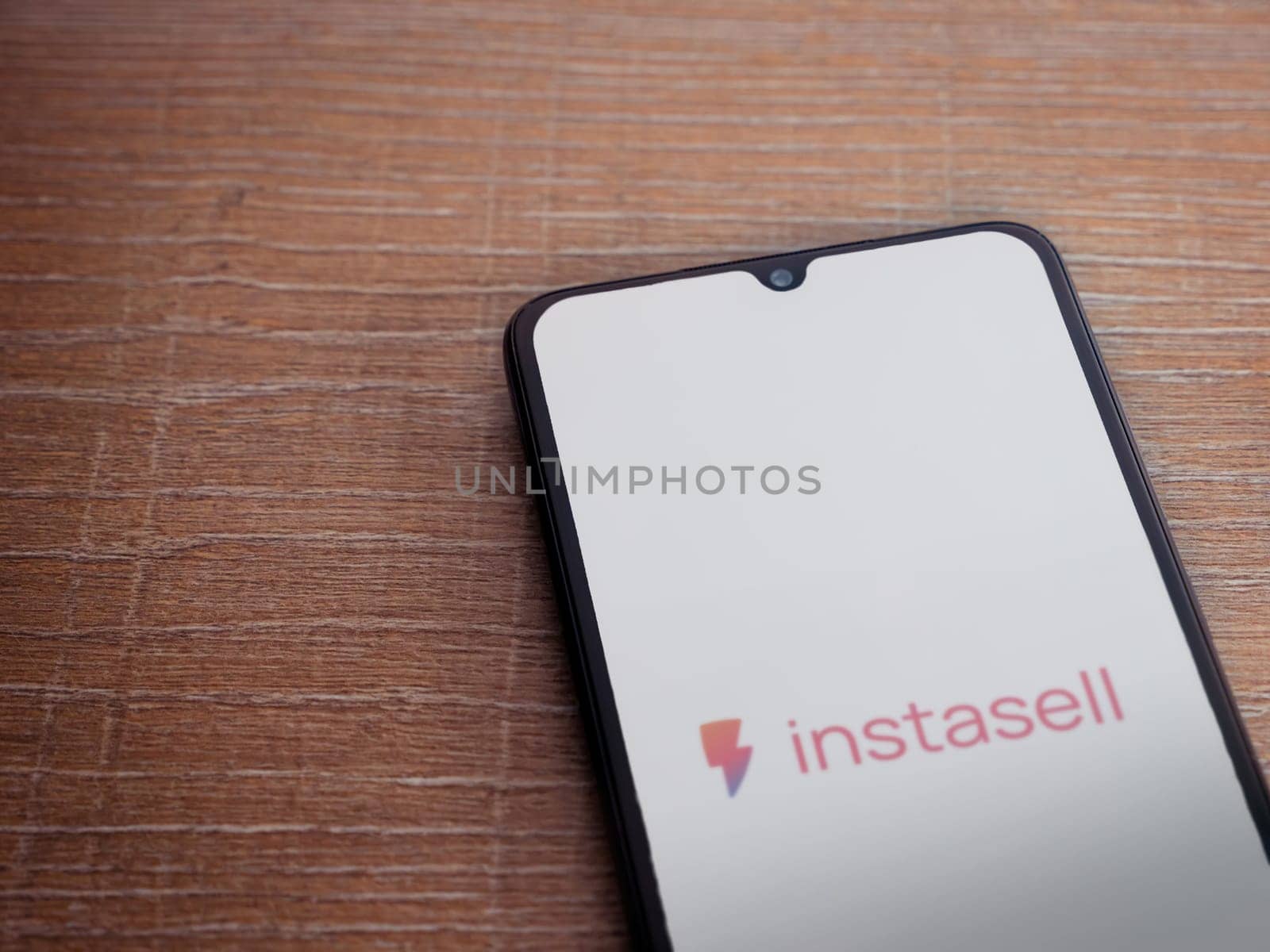 Lod, Israel - July 16,2023: Instasell app launch screen on smartphone on wooden background. Top view flat lay with copy space.