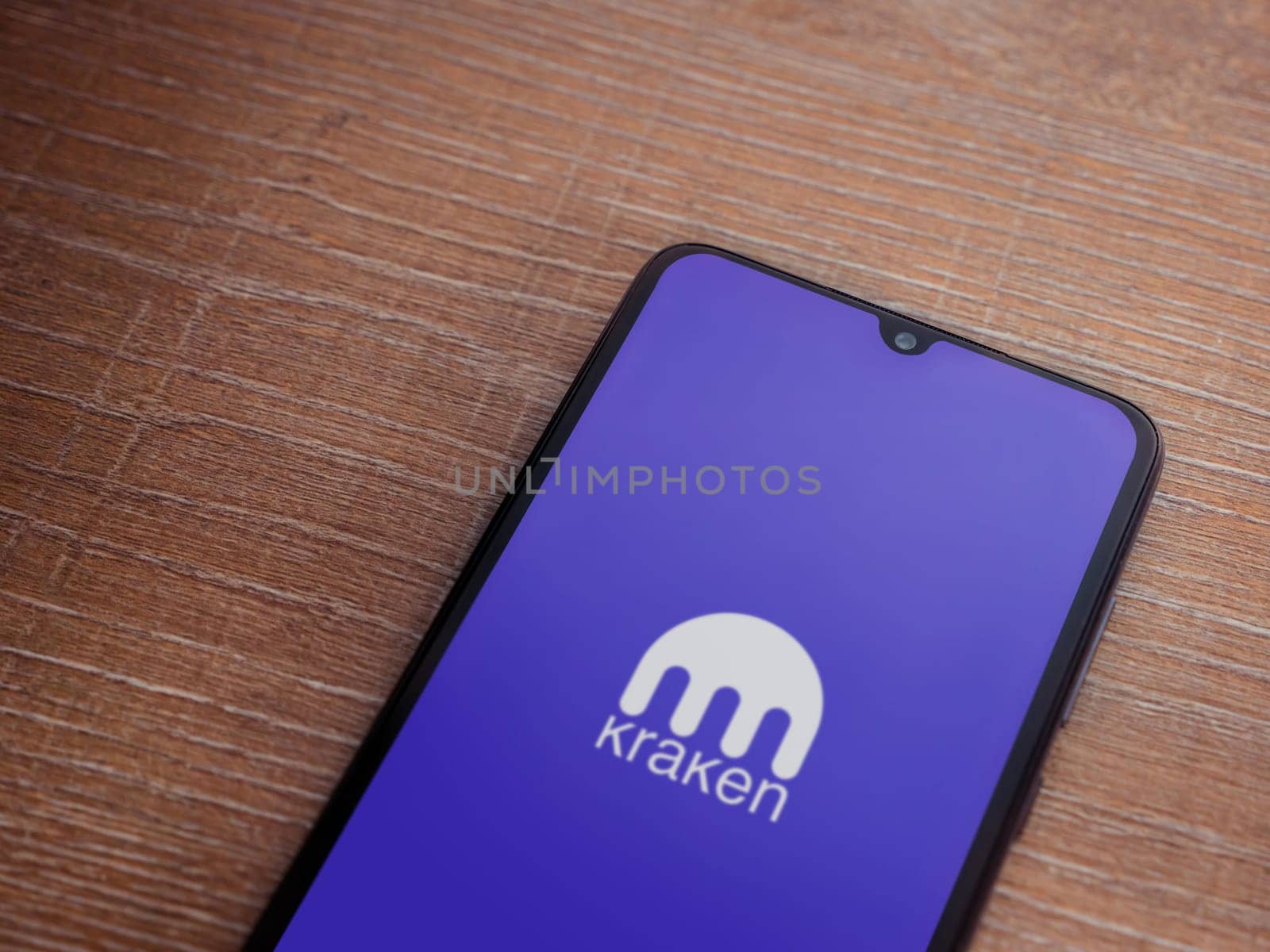 Lod, Israel - July 16,2023: Kraken app launch screen on smartphone on wooden background. Top view flat lay with copy space.