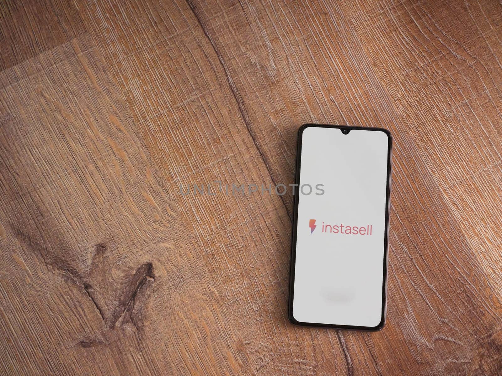 Lod, Israel - July 16,2023: Instasell app launch screen on smartphone on wooden background. Top view flat lay with copy space.