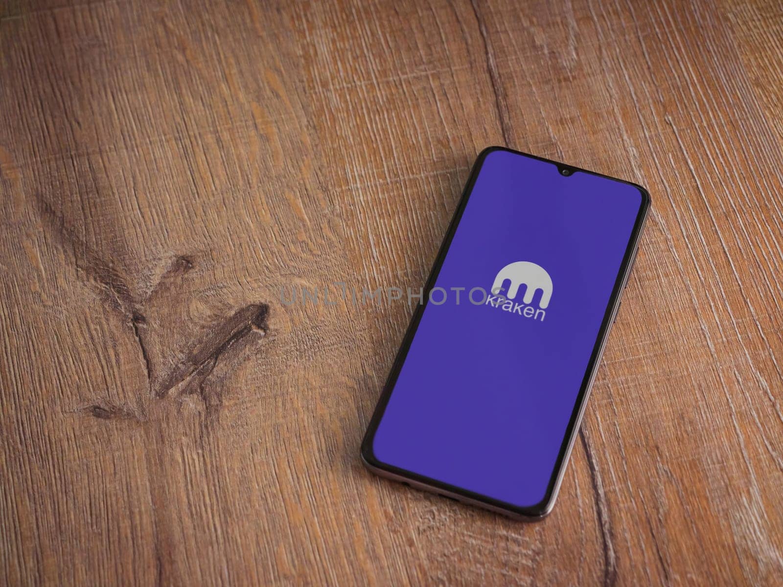Lod, Israel - July 16,2023: Kraken app launch screen on smartphone on wooden background. Top view flat lay with copy space.