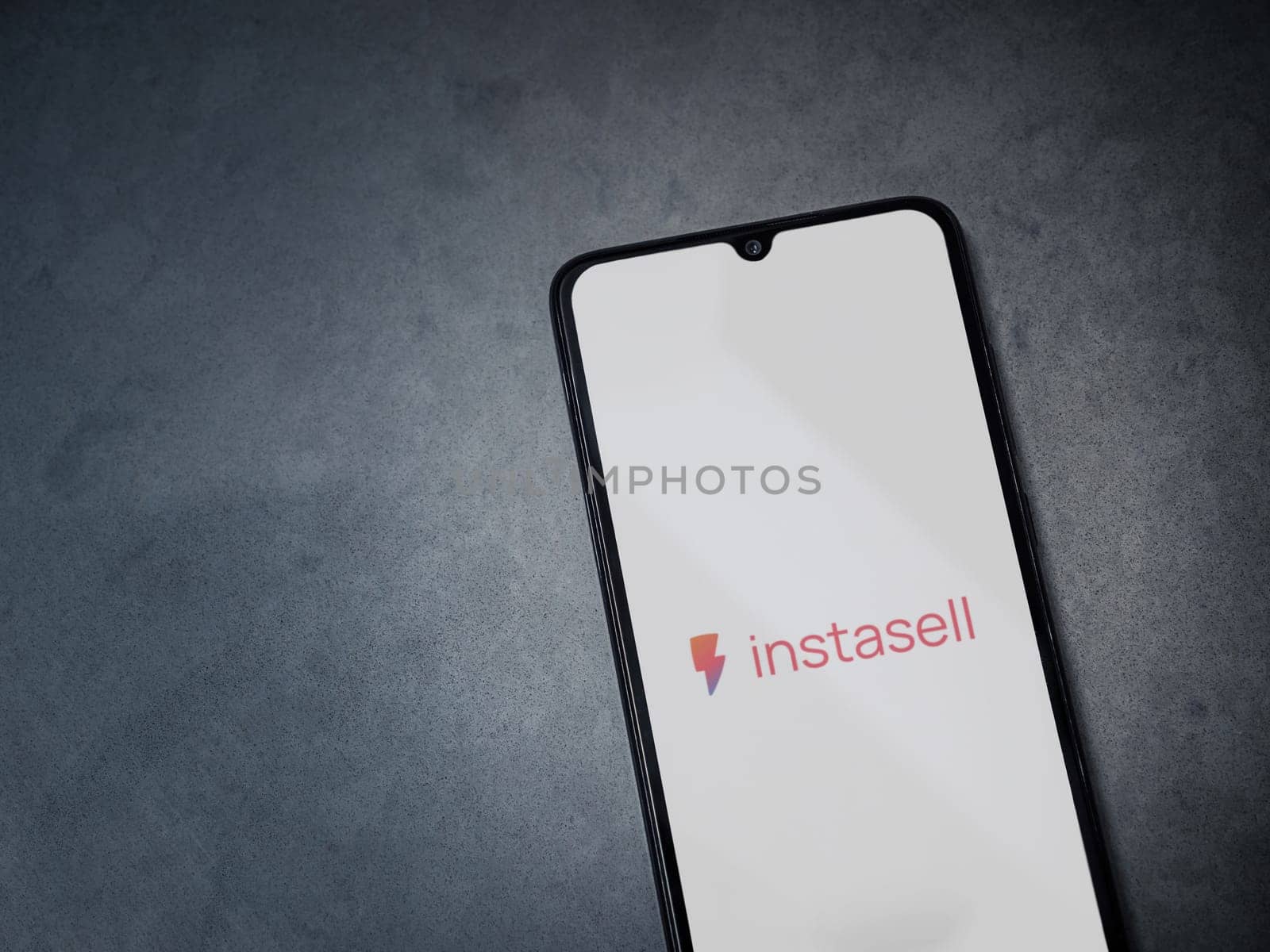 Lod, Israel - July 16,2023: Instasell app launch screen on smartphone on dark marble stone background. Top view flat lay with copy space.