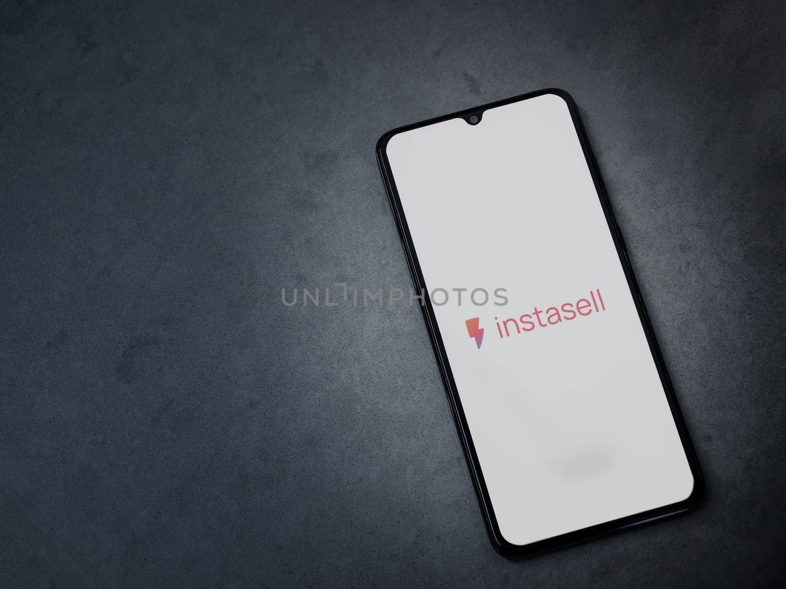 Lod, Israel - July 16,2023: Instasell app launch screen on smartphone on dark marble stone background. Top view flat lay with copy space.