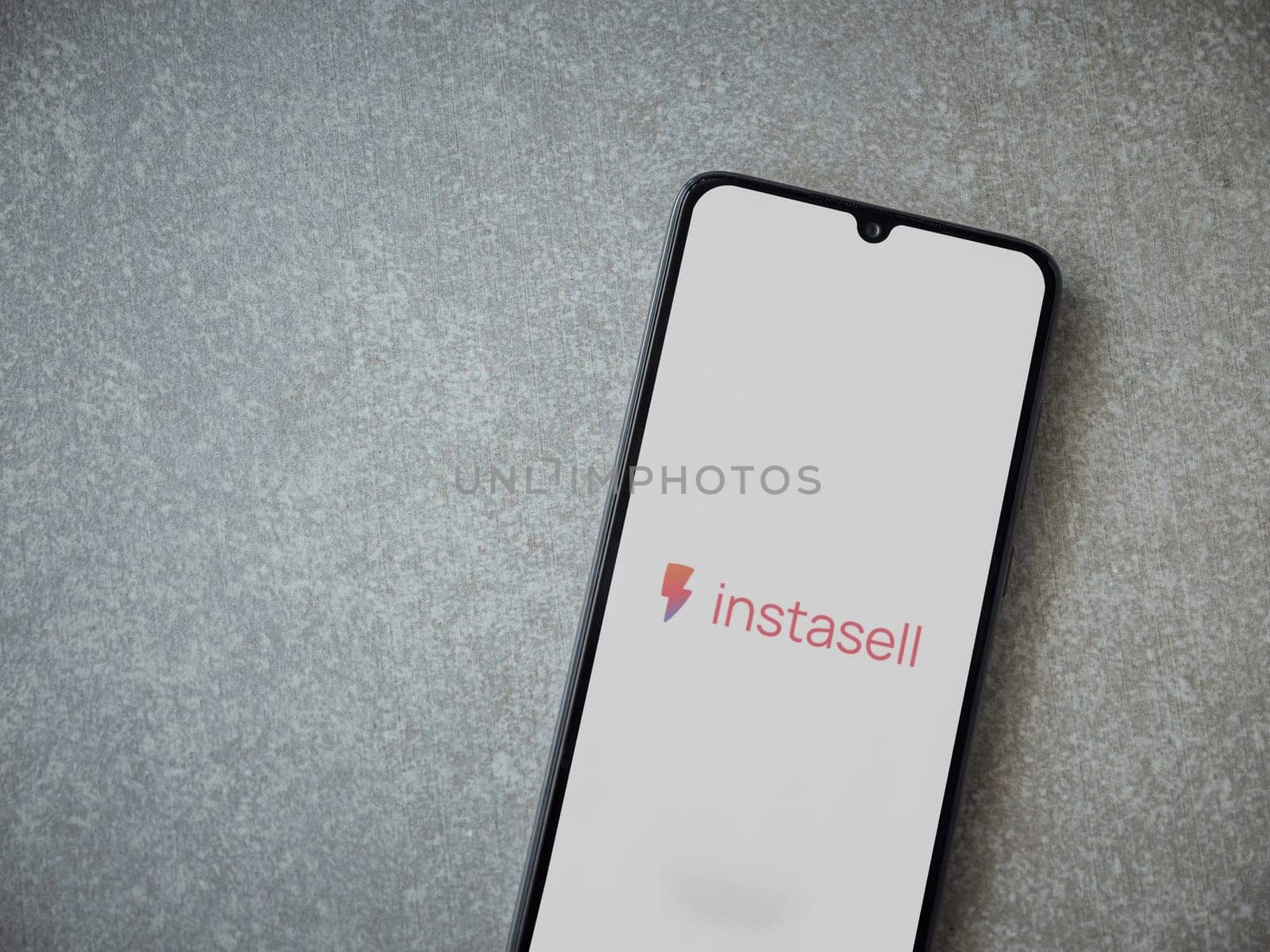 Lod, Israel - July 16,2023: Instasell app launch screen on smartphone on ceramic stone background. Top view flat lay with copy space.