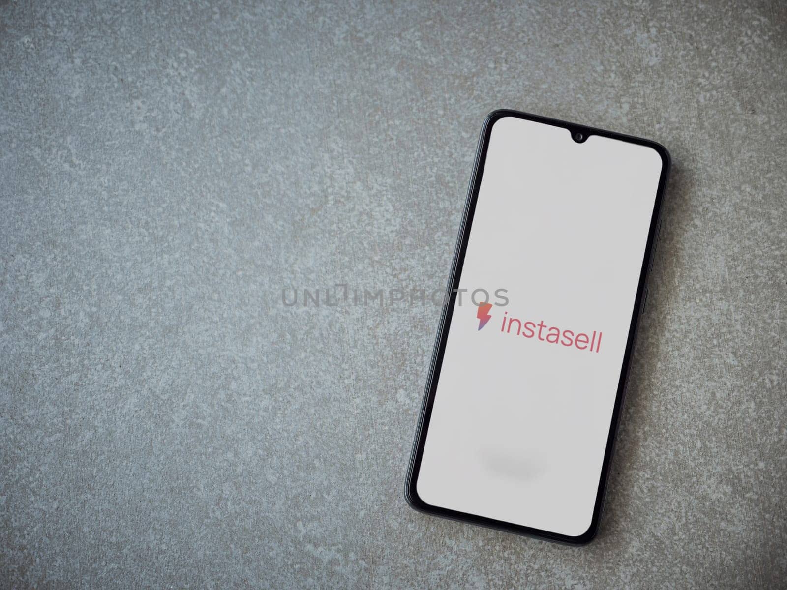 Lod, Israel - July 16,2023: Instasell app launch screen on smartphone on ceramic stone background. Top view flat lay with copy space.
