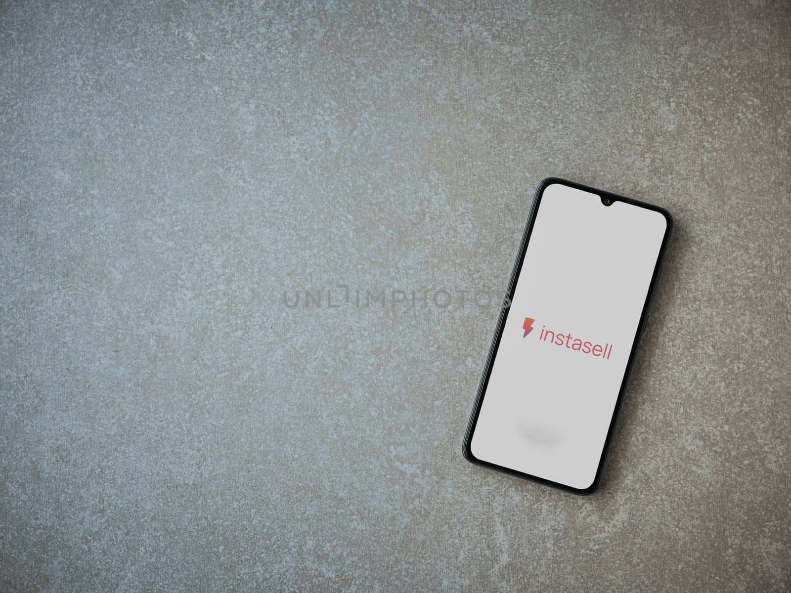Lod, Israel - July 16,2023: Instasell app launch screen on smartphone on ceramic stone background. Top view flat lay with copy space.