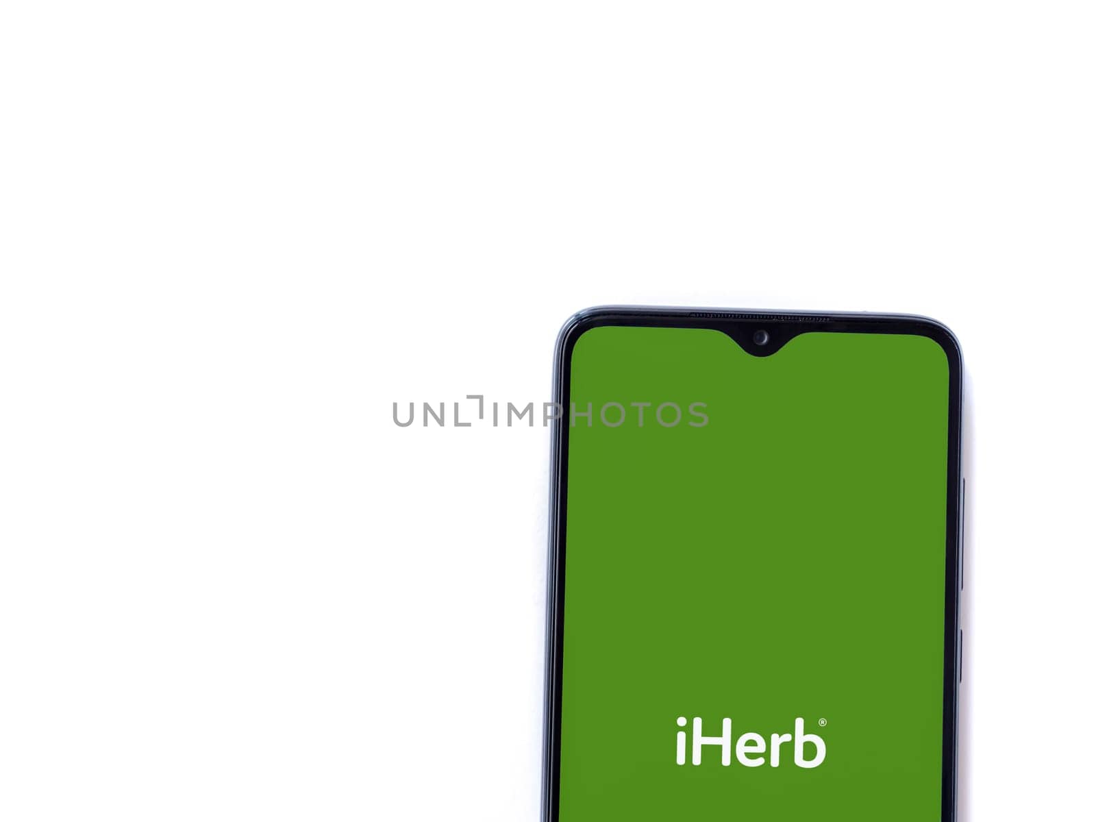 Lod, Israel - July 16,2023: iHerb app launch screen on smartphone on white background. Top view flat lay with copy space.