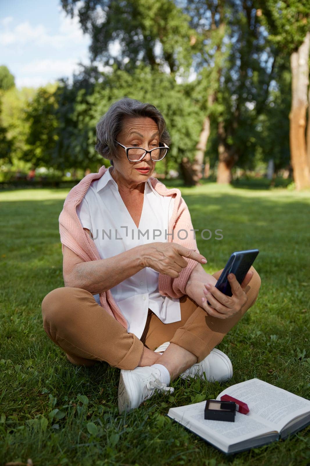Senior businesswoman using mobile phone to solve problem or making call while rest in park during break time