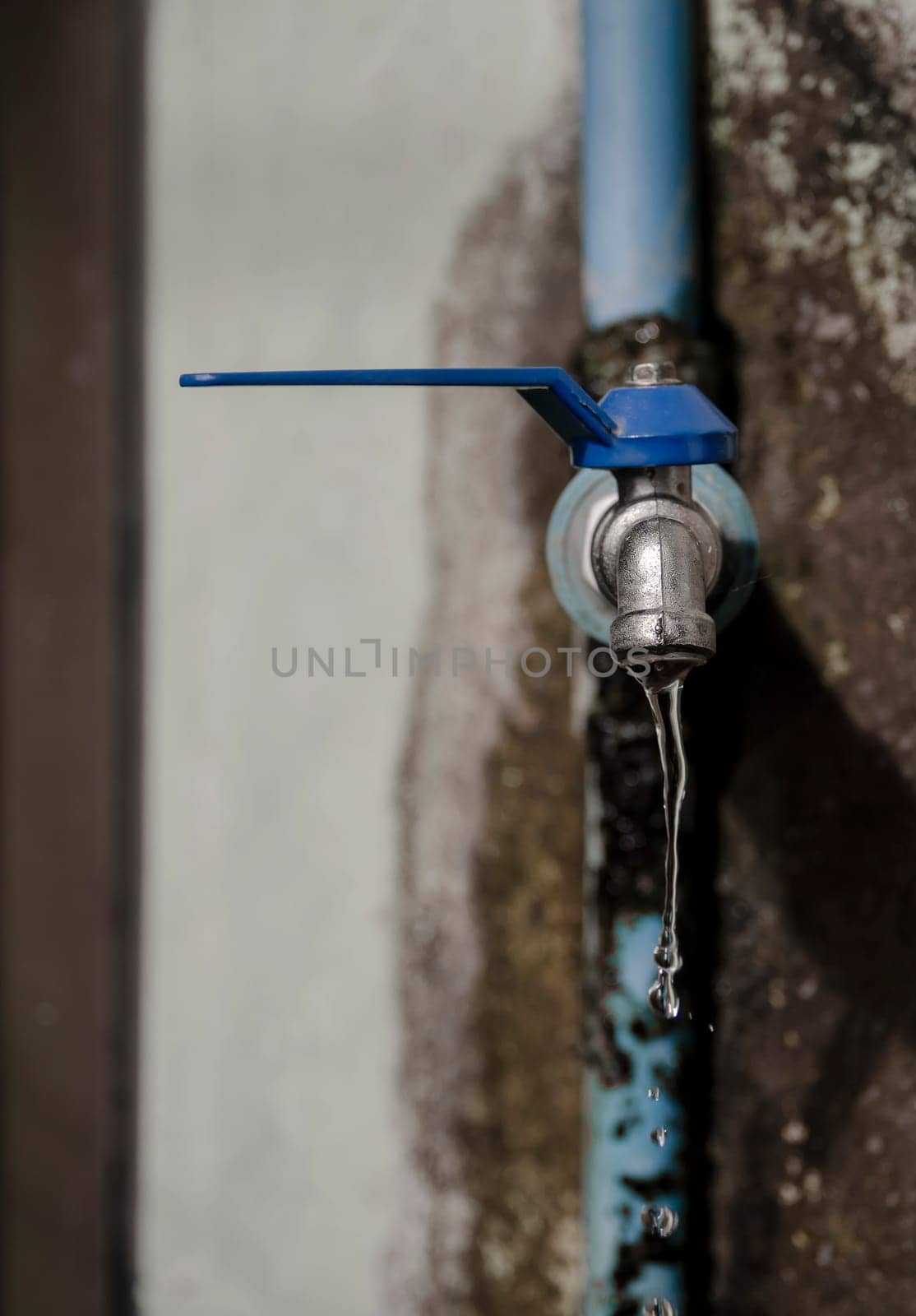 Wasting water - water drop from water tap, Leaky or tap, water tap in remote area, Deteriorated and dirty tap that everyone in the village uses to drink, which is located in a remote area It reflects the insufficiency of government agencies' water supply and the low quality of life of people in remote areas