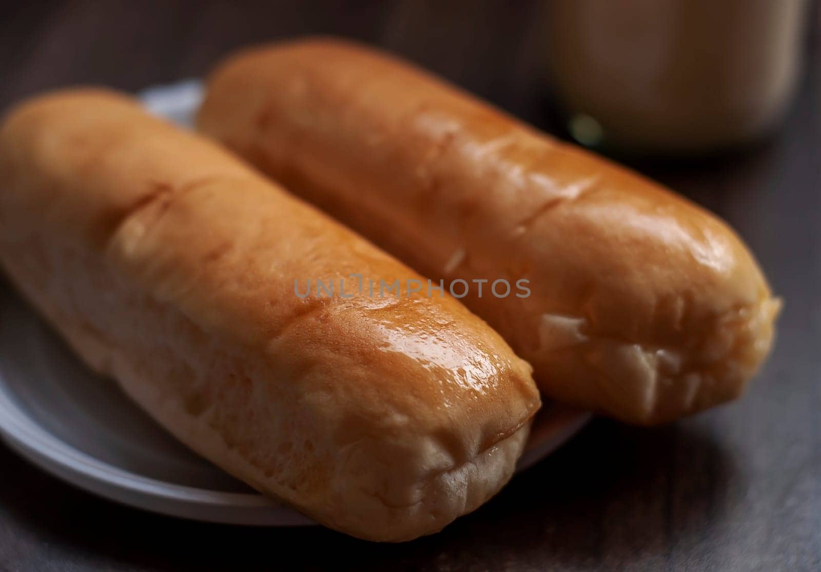 Bread on a white plate sits on a wooden board table with milk in a bottle behind it with copy space. Blurred background
