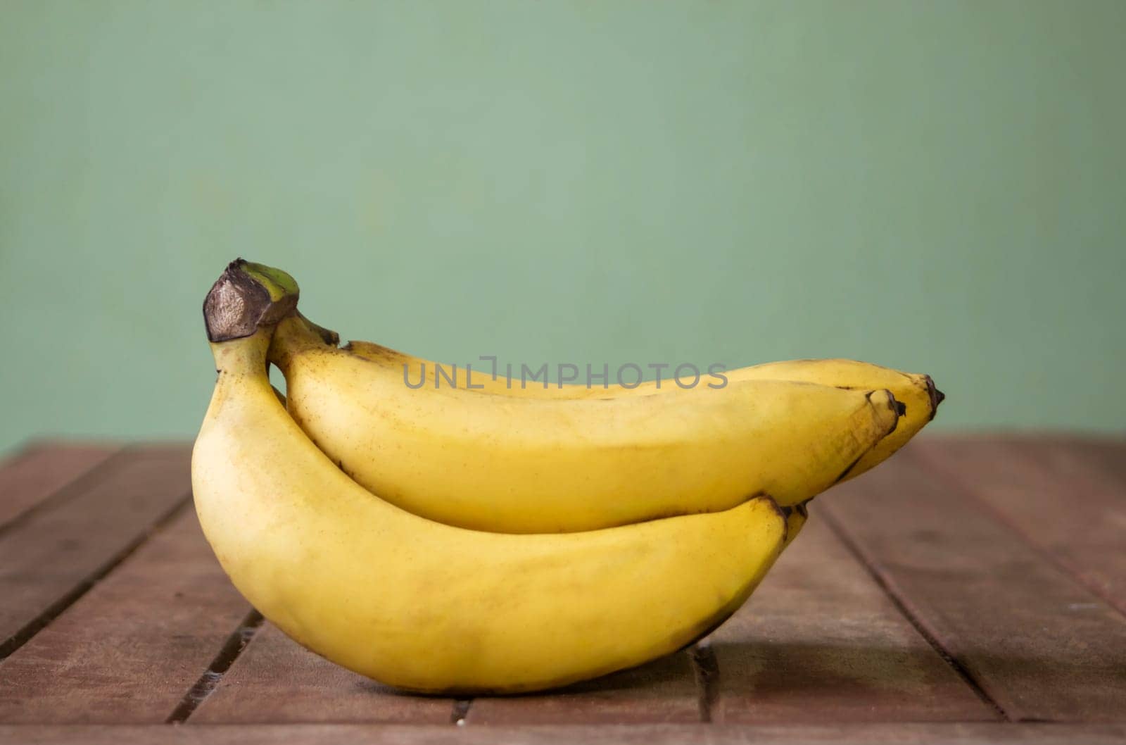 Banana fruit with wooden table on blurred green background