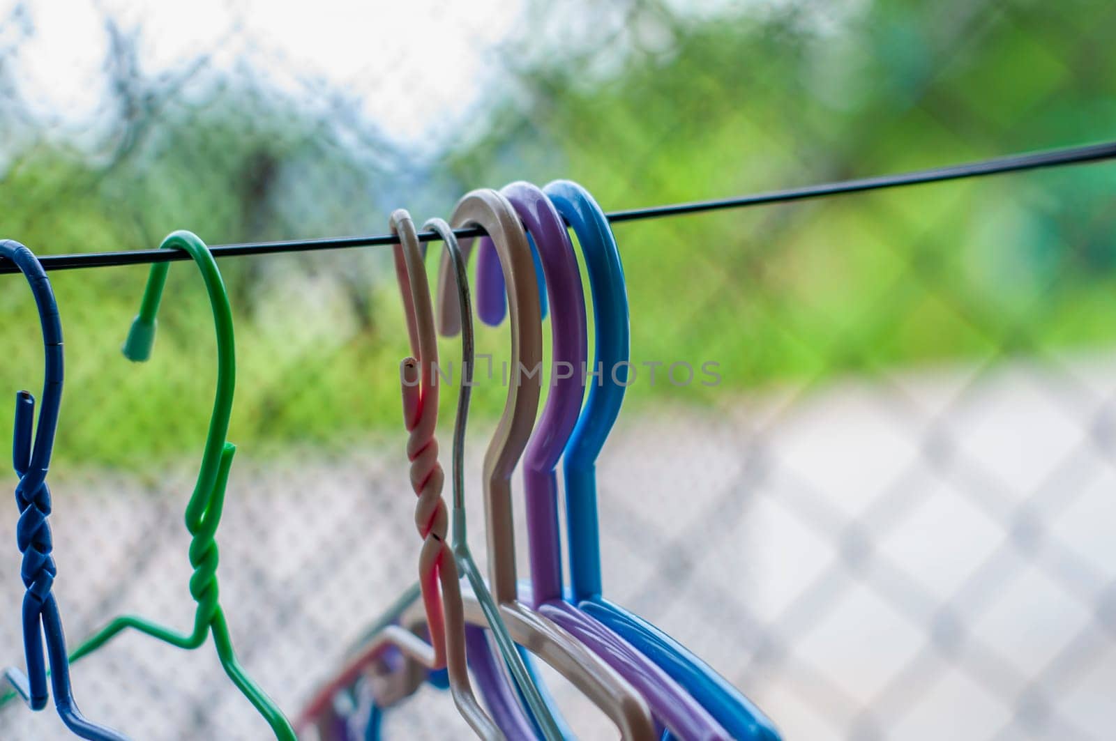Hangers of various colors hung on a clothesline made of wires blurred background, It is a way of life for people in rural areas far from civilization in the south of Thailand.