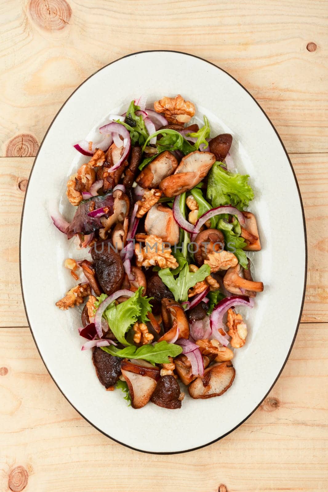 Homemade salad with roasted mushroom, red onion, herbs and walnuts. Healthy vegetarian food