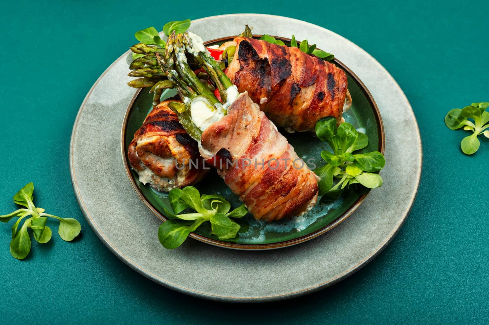Baked roulades wrapped in bacon. Meat stuffed with asparagus on a plate.