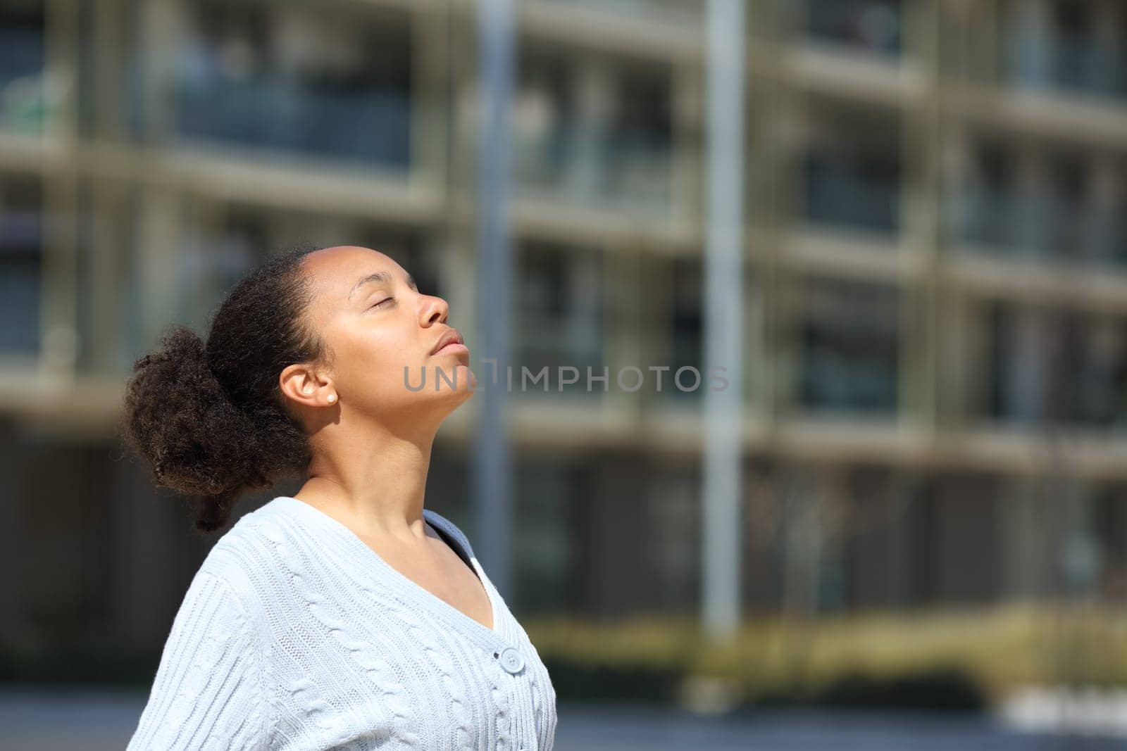 Serious black woman breathing fresh air in the street