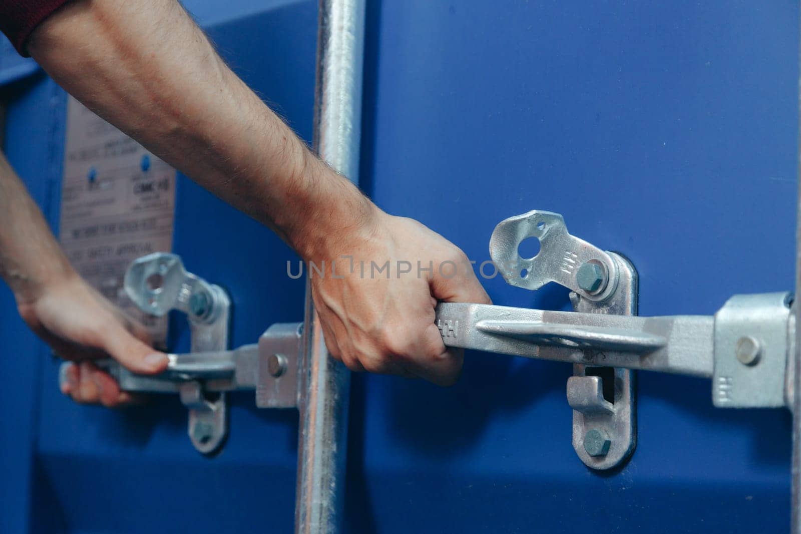 Close up view on man hands is opening the lock of large shipping container doors.