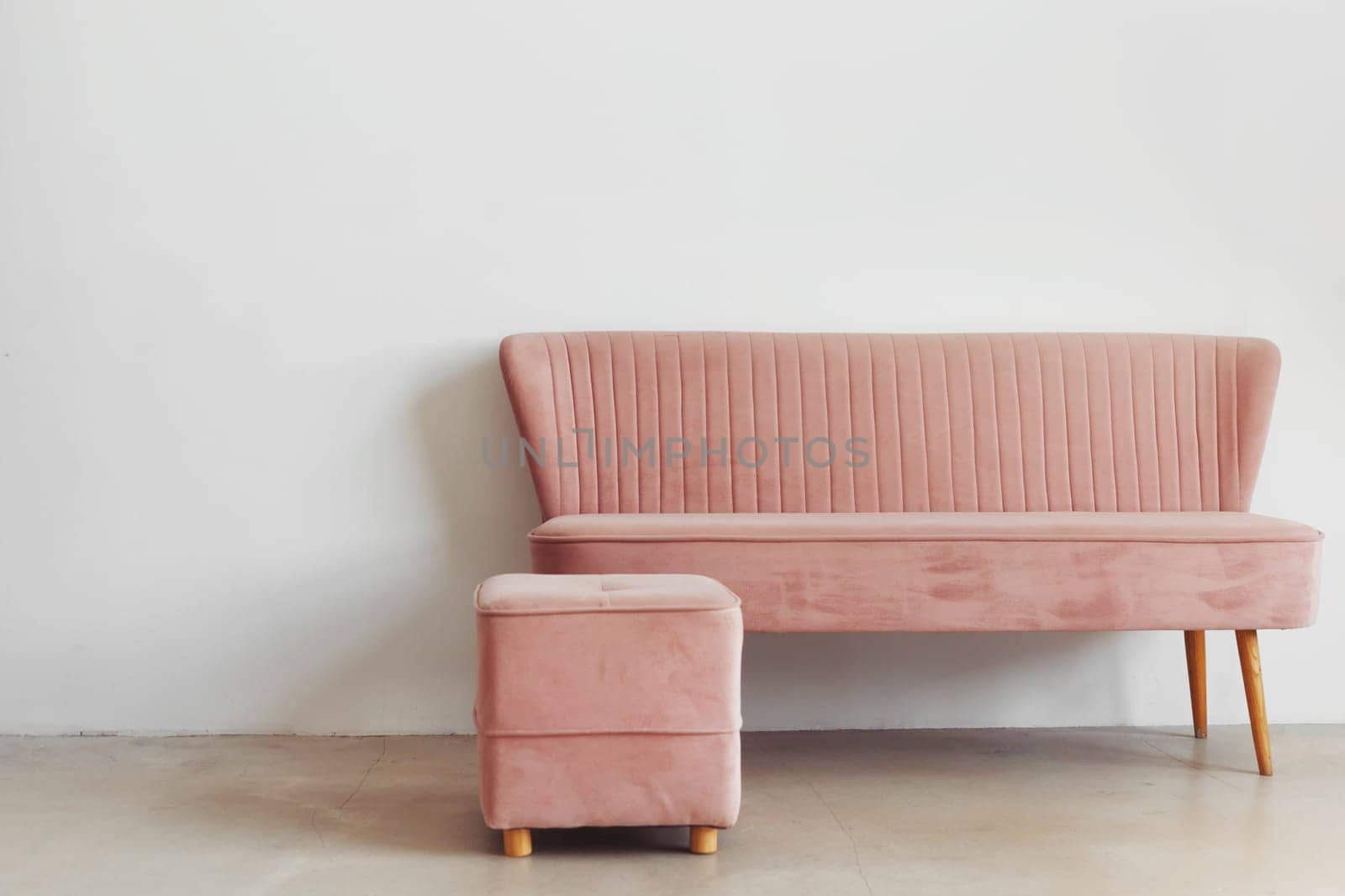 Minimalist composition of room interior with pink pouf and sofa against white wall, copy space