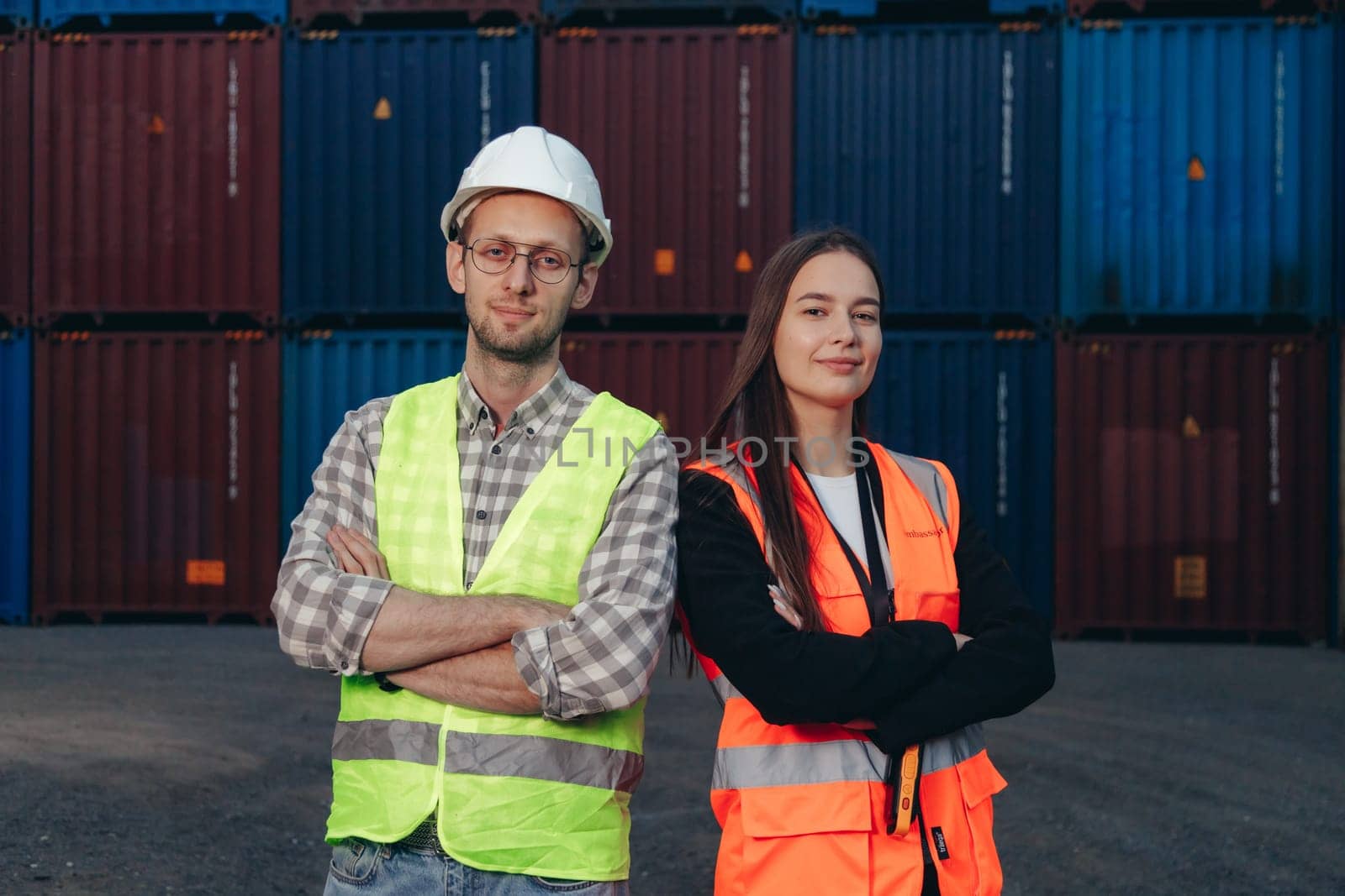 Two technician workers, man and woman, standing side by side in shipping terminal.