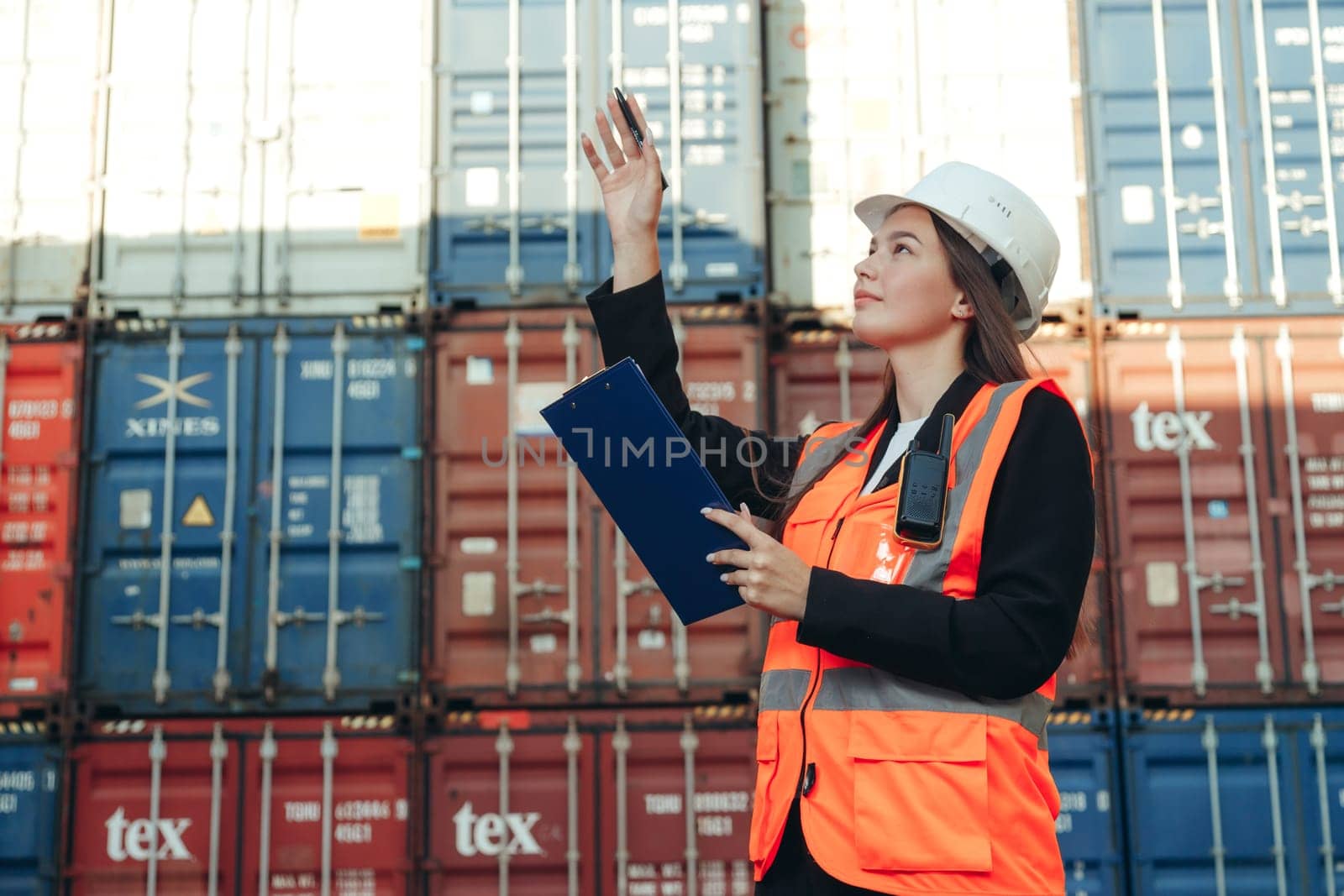Female engineer with clip folder wearing white helmet and vest in container terminal port