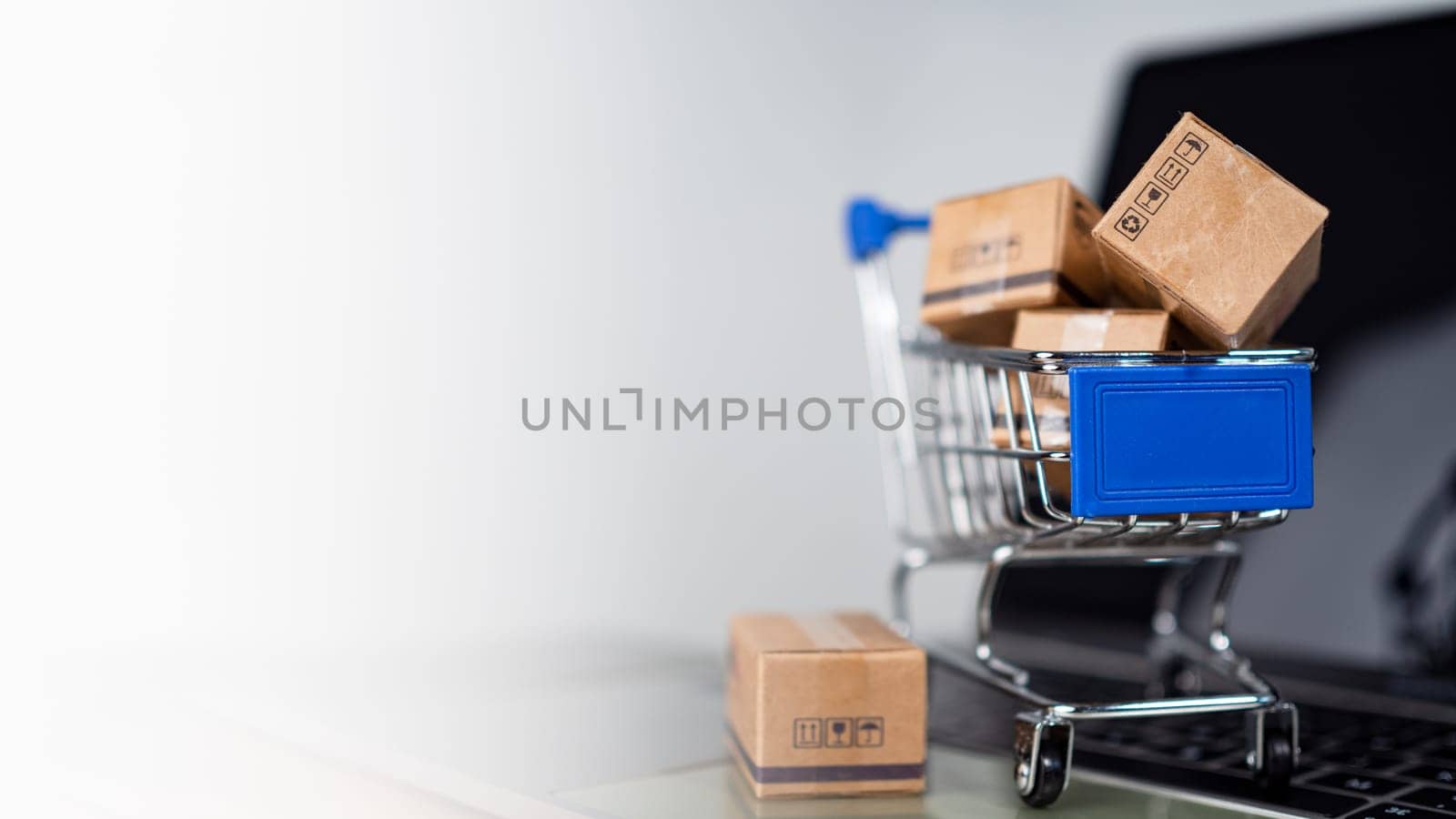 Shopping cart and product boxes on laptop computer on white background and copy space. online shopping marketplace platform website E-commerce technology, shipping, logistics and online payment concepts.