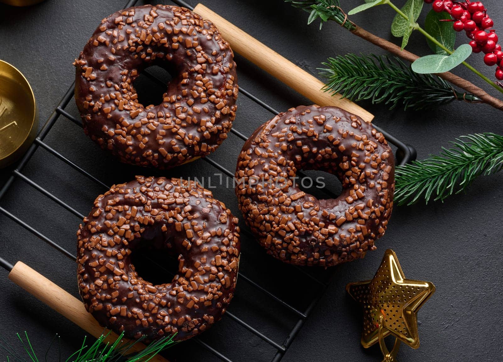 Chocolate donuts sprinkled with crushed nuts on a black table