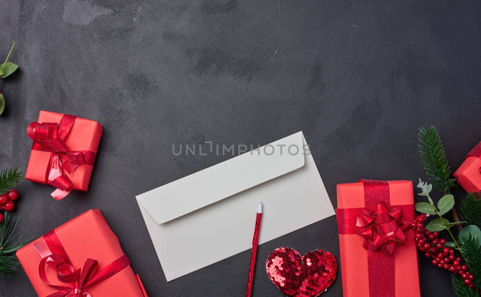 Christmas decor, gifts wrapped in red paper and a letter on a black background, top view