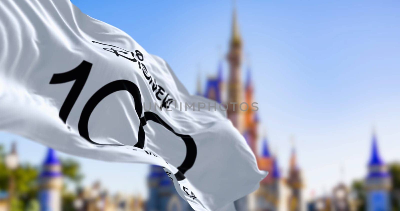 Orlando, US, October 10 2023: Celebratory flag for the 100th anniversary of the Walt Disney Company waving in the wind. Illustrative editorial 3d illustration render