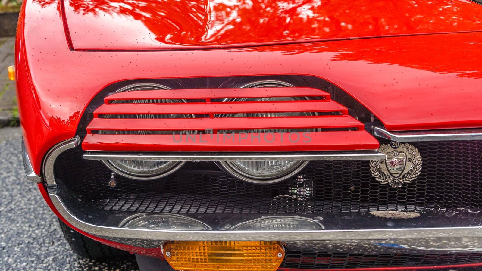 WETTENBERG, HESSE, GERMANY - 07 - 28 - 2023: Double headlights of an Alfa Romeo Montreal eight-cylinder in red from the 1970s at the Golden Oldies classic car show in the Wettenberg Krofdorf-Gleiberg near Gießen in Hesse