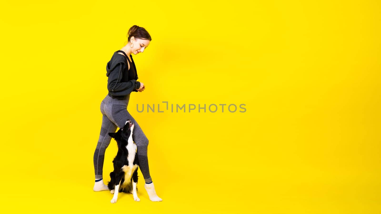 Shot of sport female in leggings with a border collie dog isolated on yellow and red background