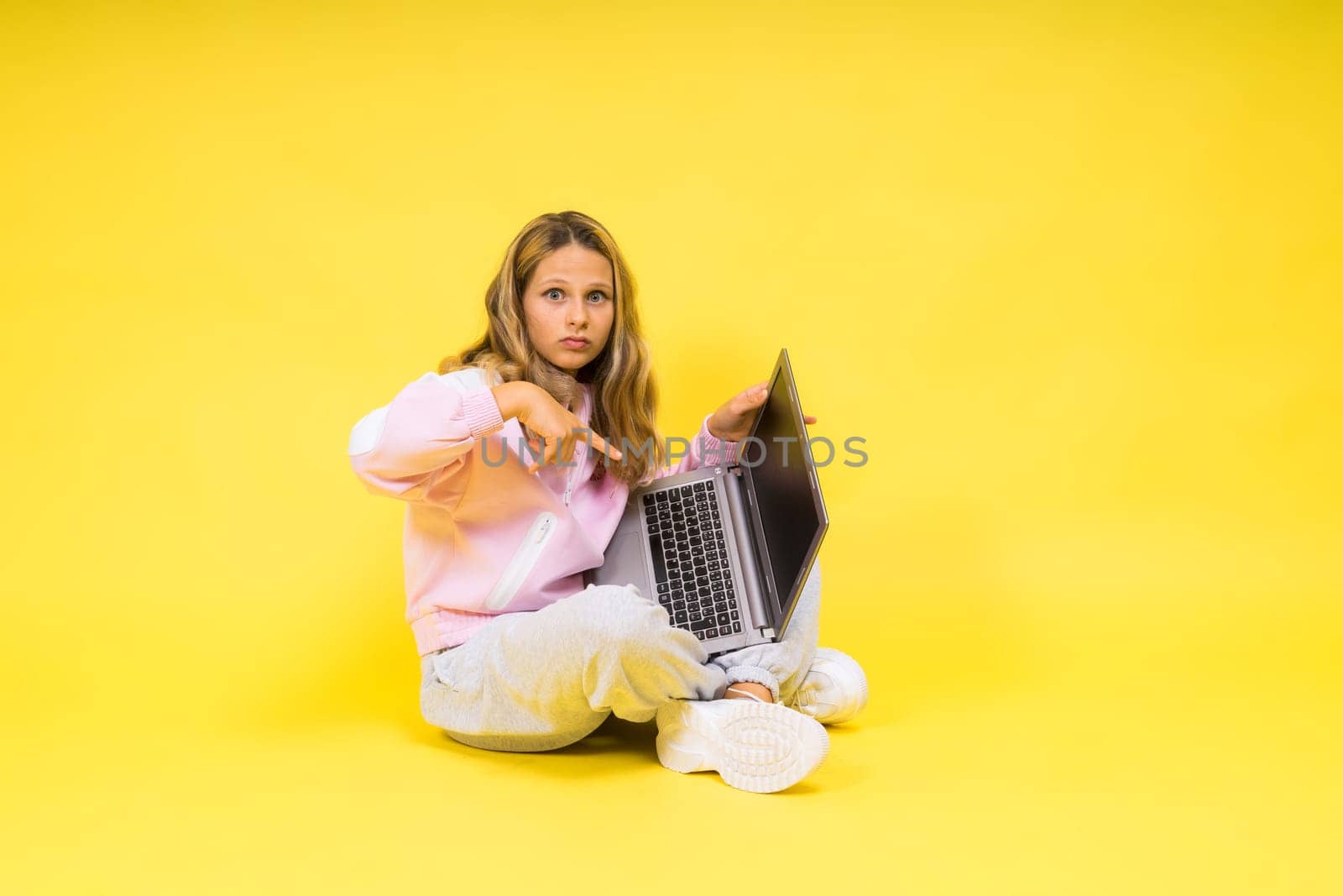 Fitness online. Girl doing stretching exercise on a floor alone with laptop at studio