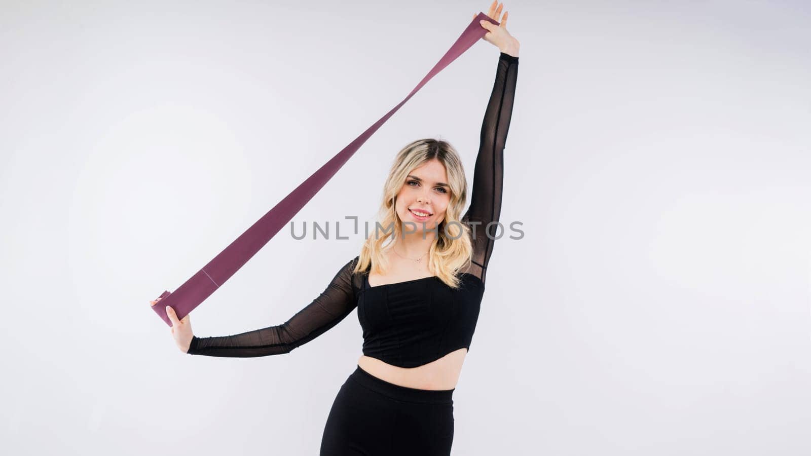 Young woman workout with resistance band on a white background. Strength and motivation.
