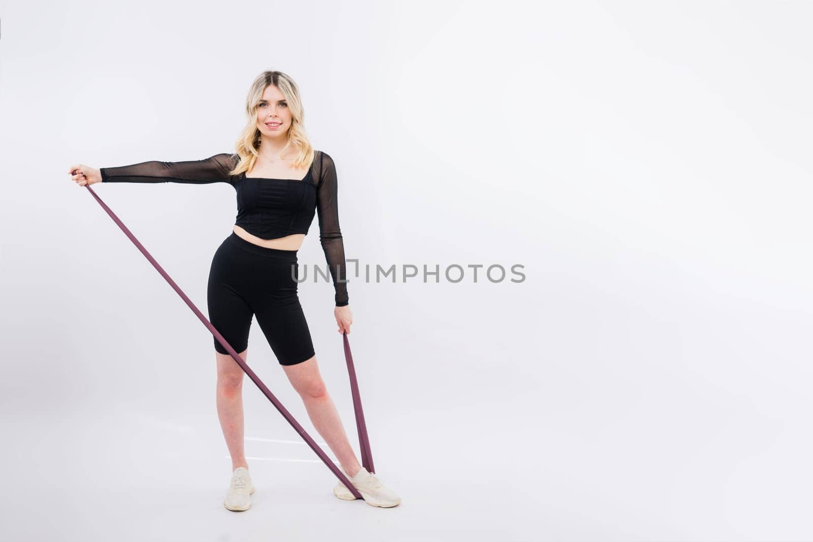 Young woman workout with resistance band on a white background. Strength and motivation.