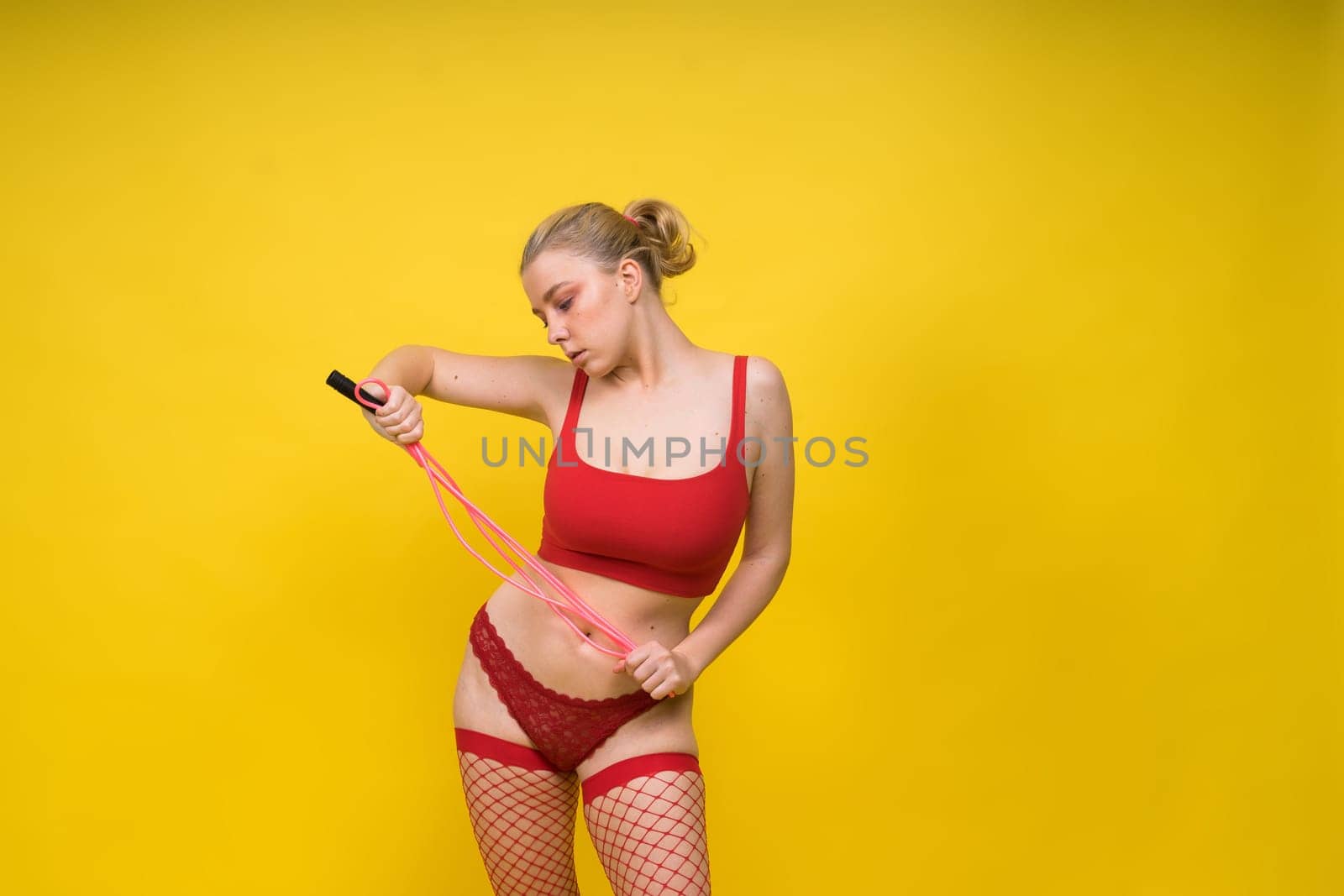 Beautiful fitness female posing in studio background with jumping rope