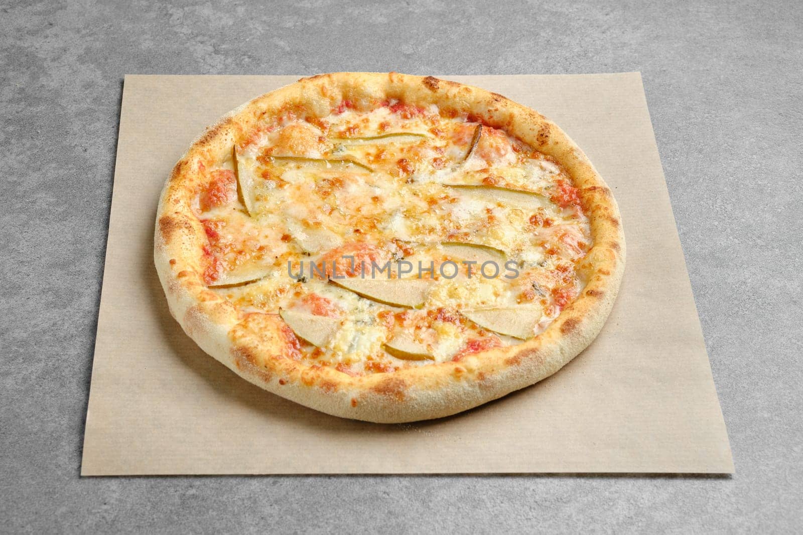 Pizza with blue cheese and slices of pear on parchment paper