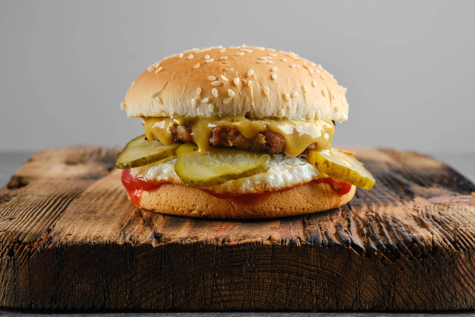 Burger with fried egg and pickled cucumber front view
