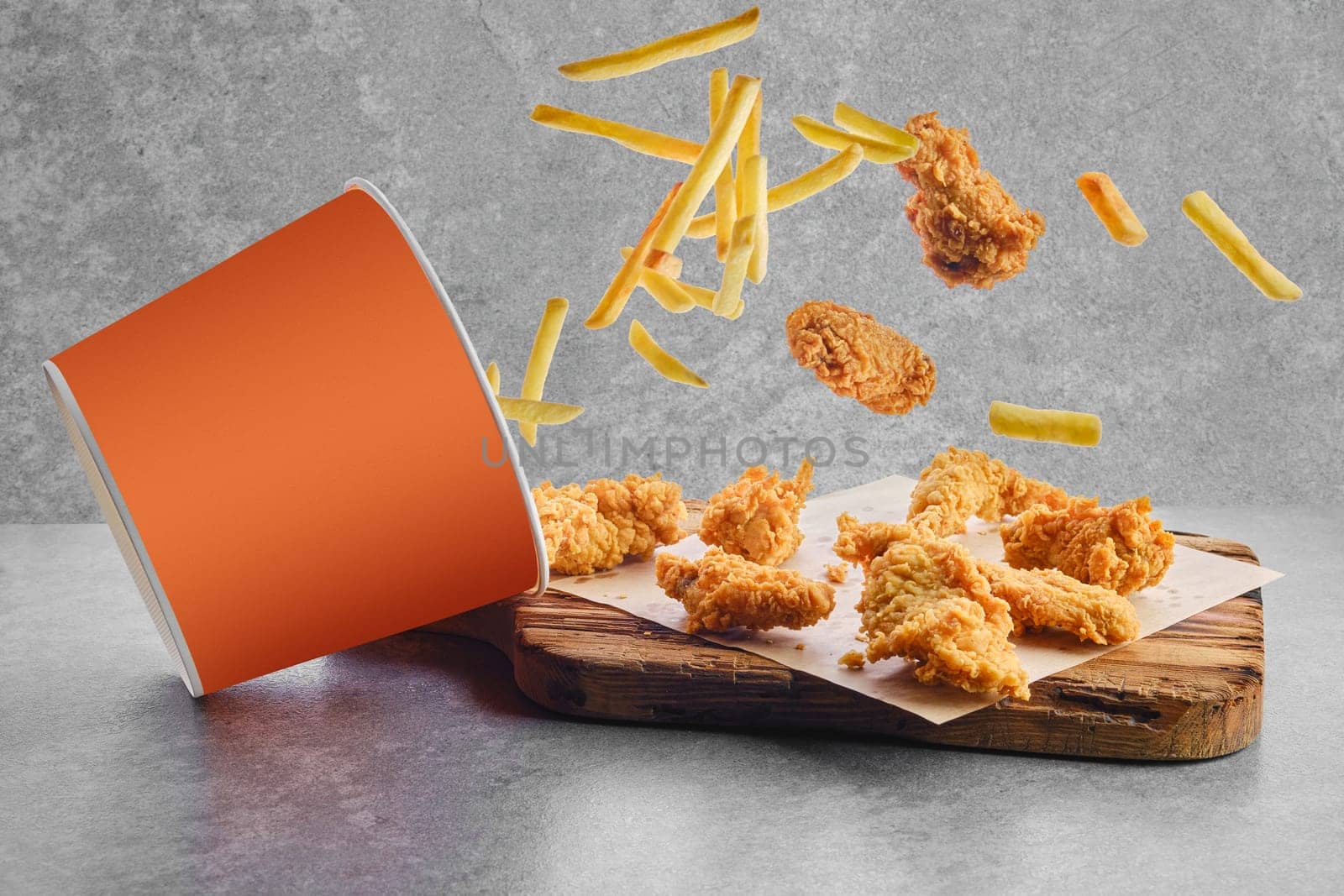 Deep fried chicken wings and nuggets in breading scattered from basket on parchment paper