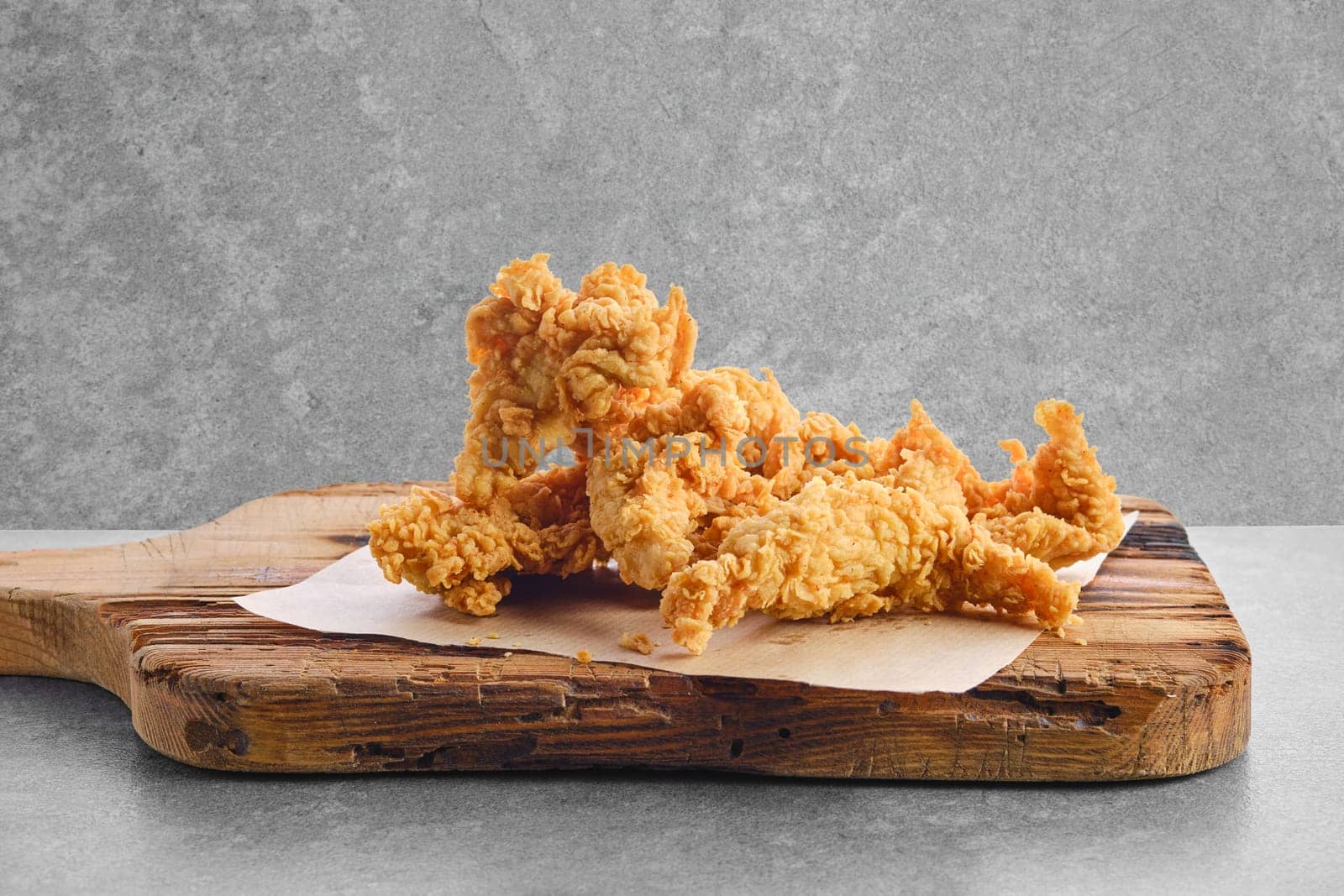 Deep fried chicken nuggets in breading on wooden serving board
