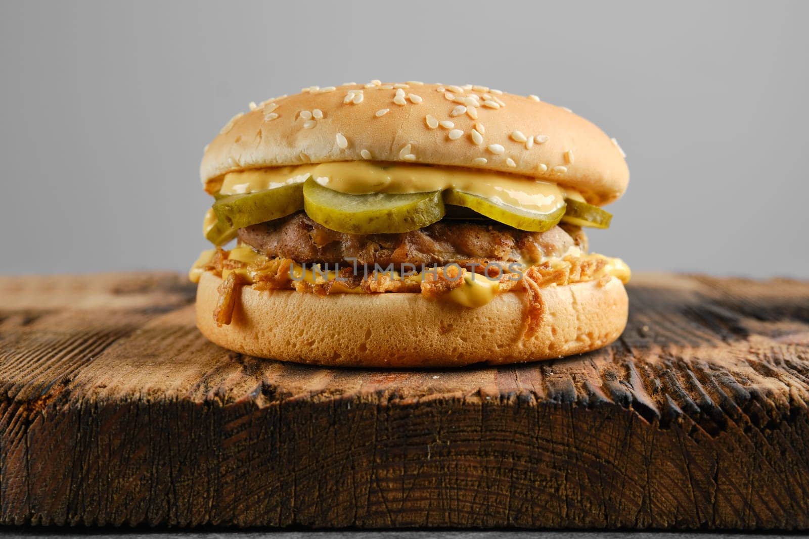 Beef burger with pickled cucumber and onion crumbs front view