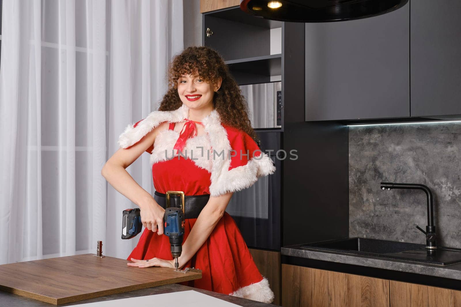 Smiling snow maiden installing hinges on kitchen cabinet door