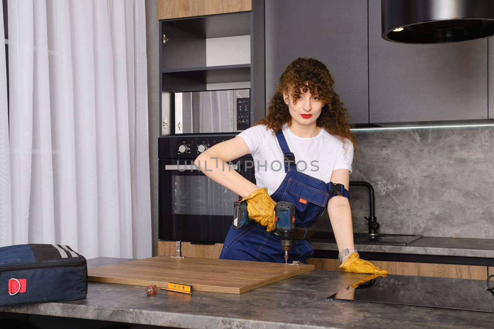 Young woman installing hinges on kitchen cabinet front