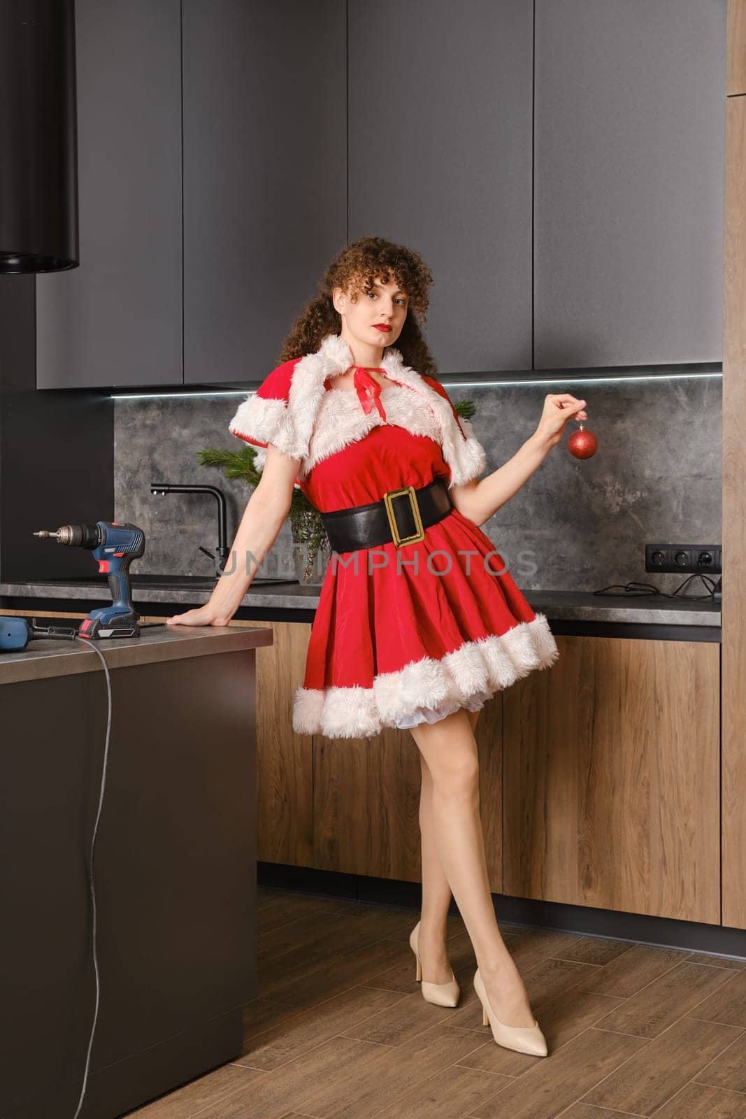 New Year's themed furniture assembly concept. The snow maiden standing near kitchen table with toy ball in hand.