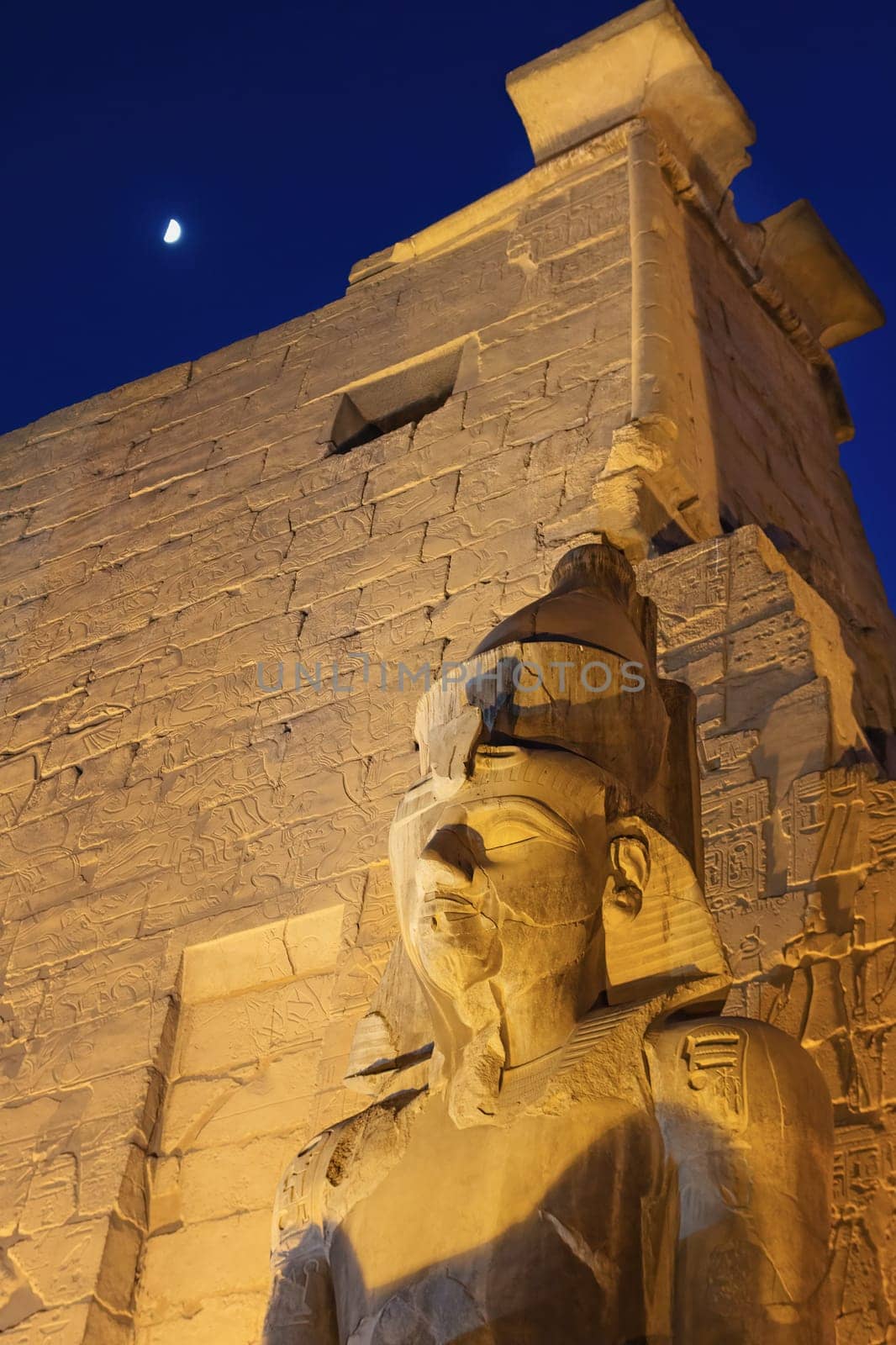 Night view of  Statue Of Ramesses II. by The Luxor Temple Luxor. Egypt. Shining moon is in the background. Vertically,