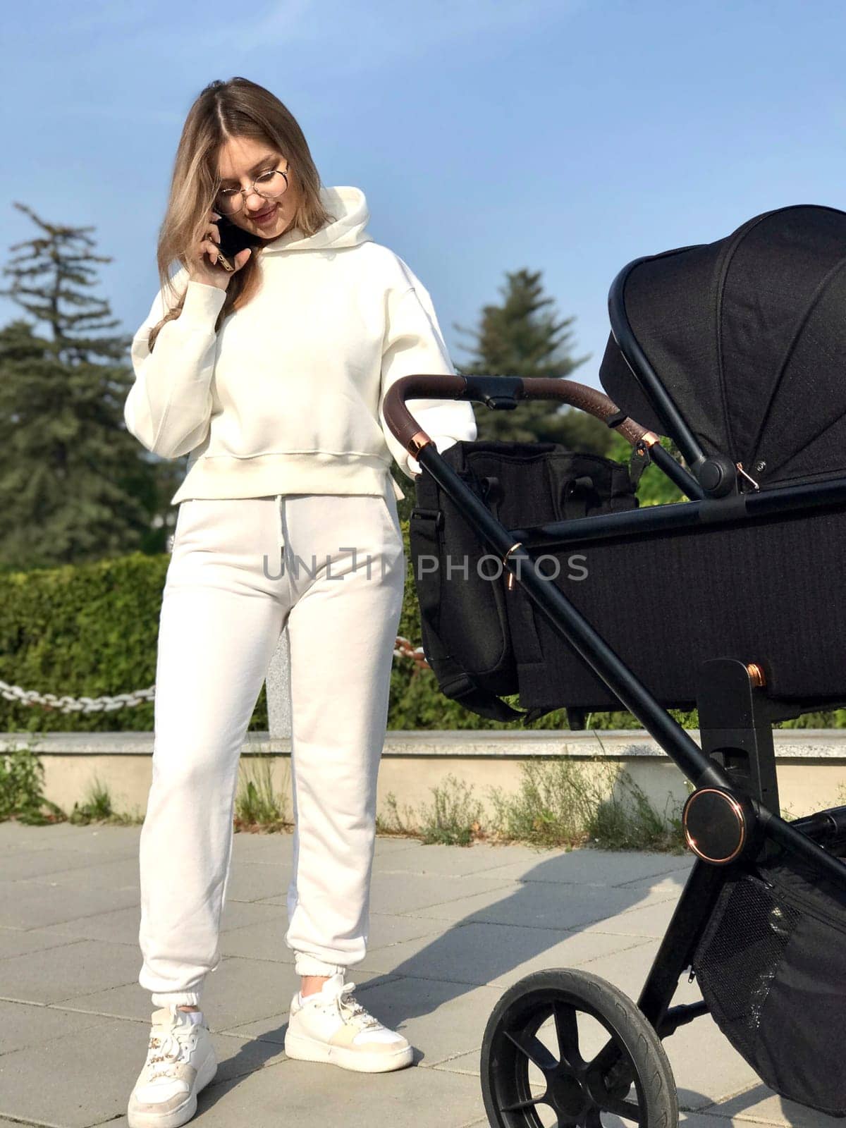 young pretty woman with straight long hair and wearing white sportswear walks with baby.