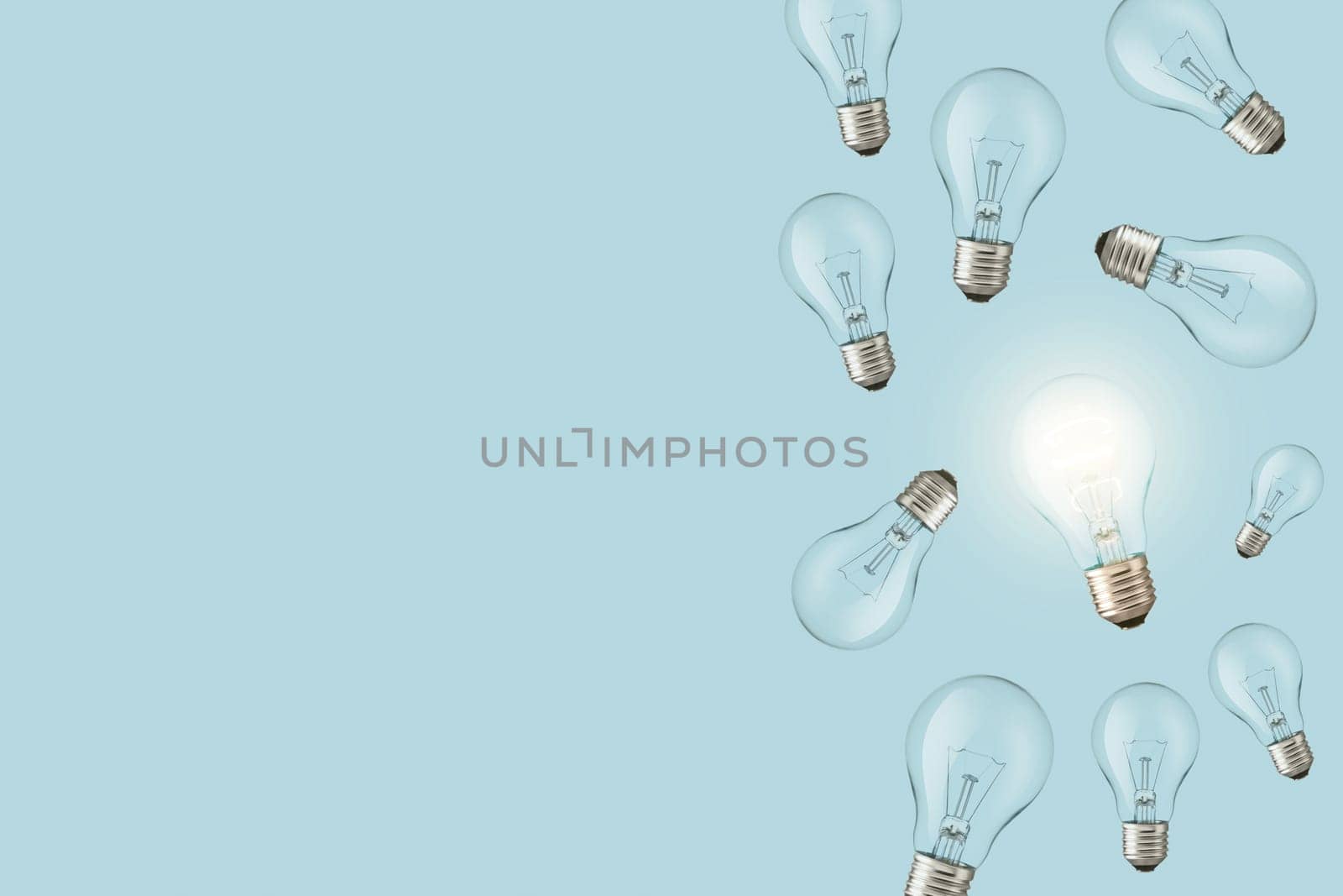 Light bulbs on a blue background and one creative glowing light bulb. Creative idea, concept. Electricity and think differently.