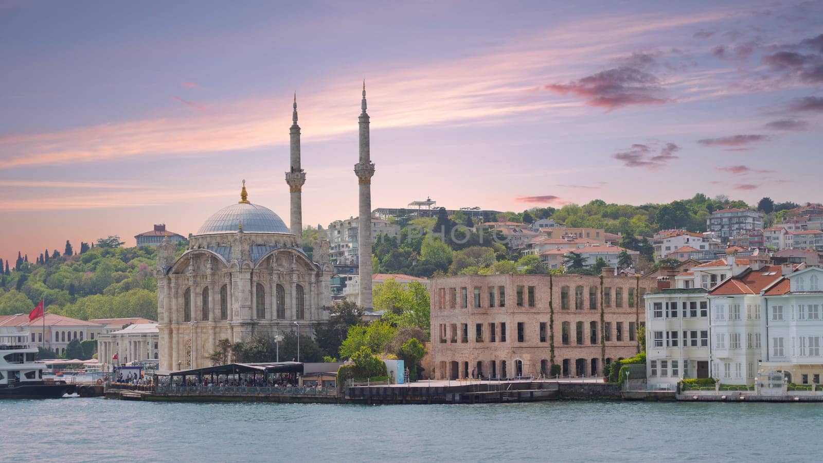 Istanbul, Turkey - May 8, 2023: View from Bosphorus Strait overlooking Ortakoy Mosque and redeveloped Esma Sultan Mansion, currently a Cultural center, Ortakoy pier square before sunset