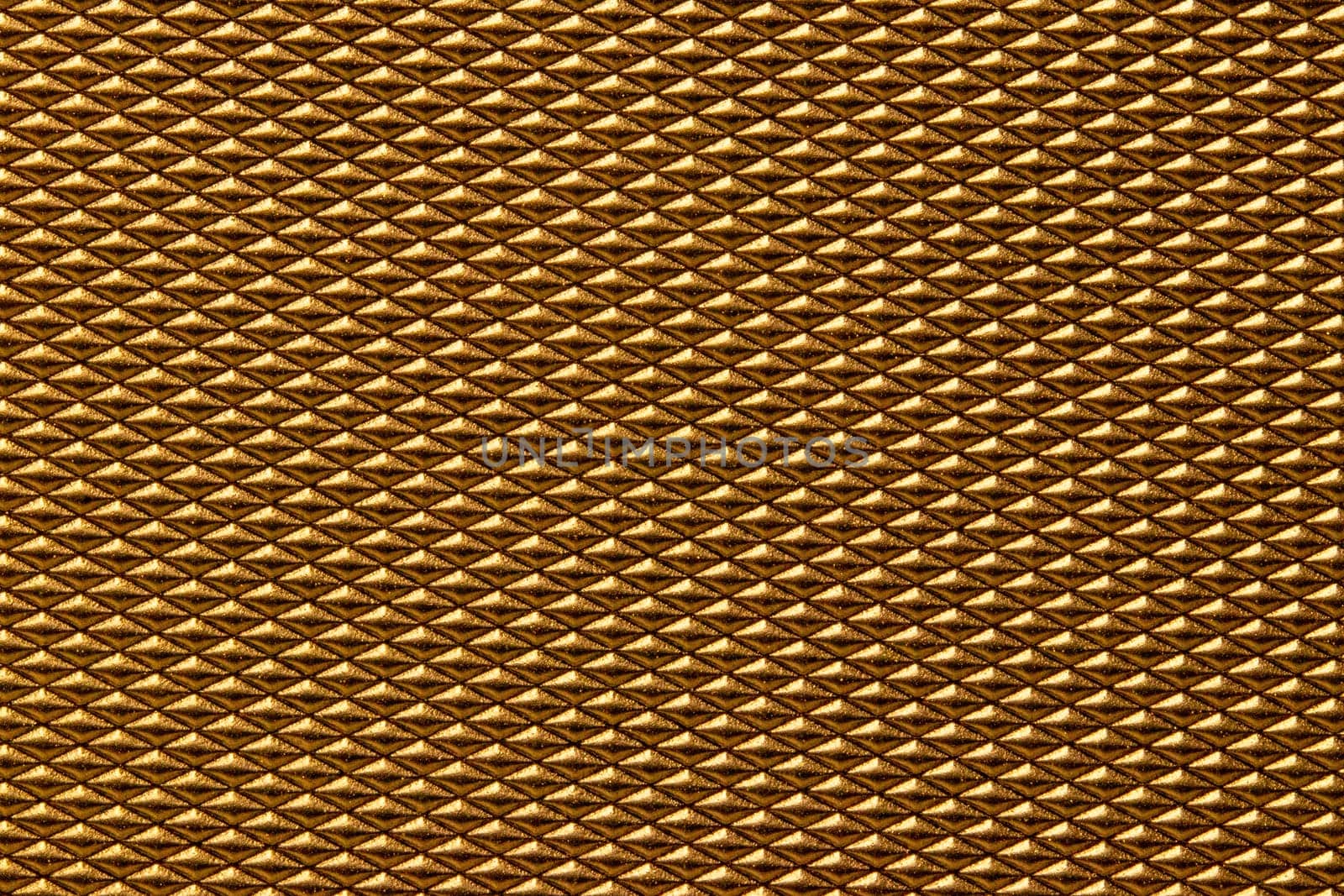 Seamless plastic texture background. Close-up of a detail from a gold glittering surface of a cosmetic bag. Beautiful backdrop. Macro.