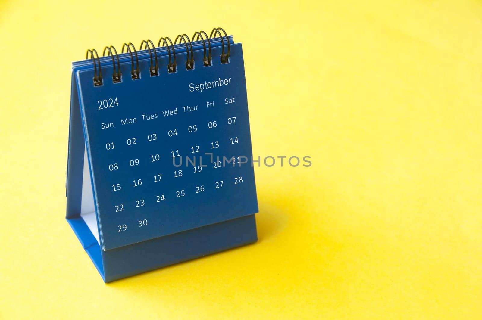 September 2024 blue desk calendar on yellow cover background with customizable space for text. Copy space and calendar concept.