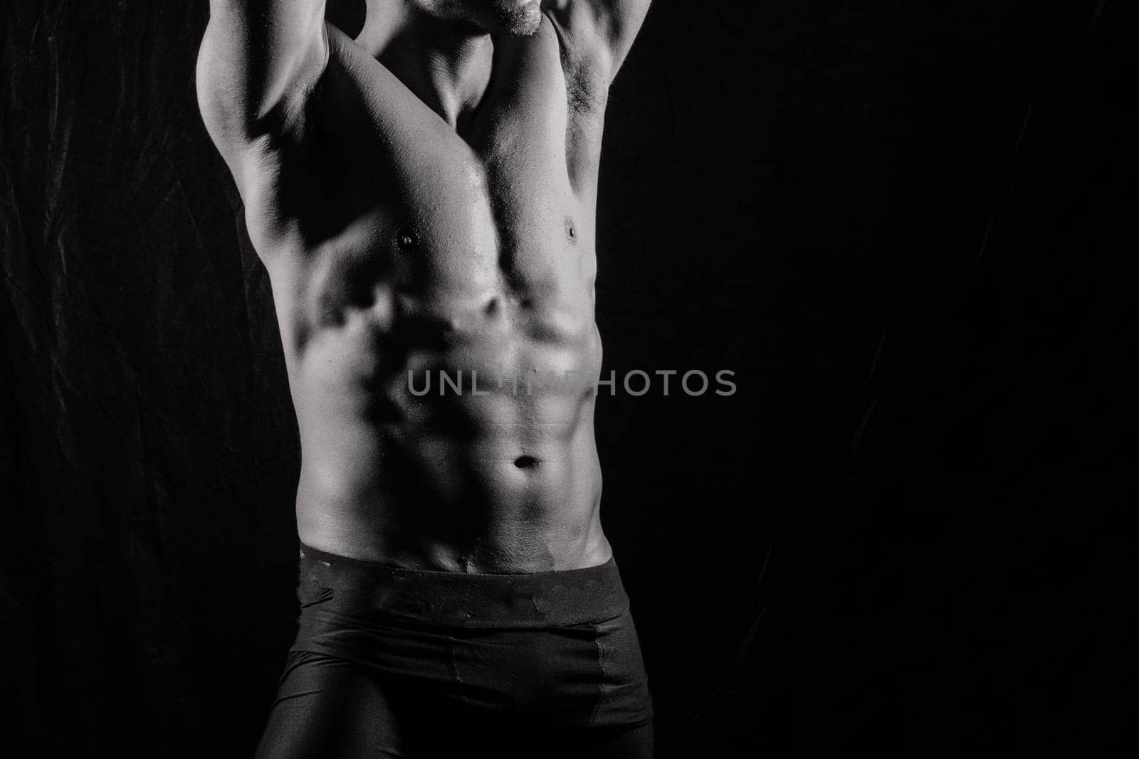 Confident, attractive shirtless muscular young man topless in a studio