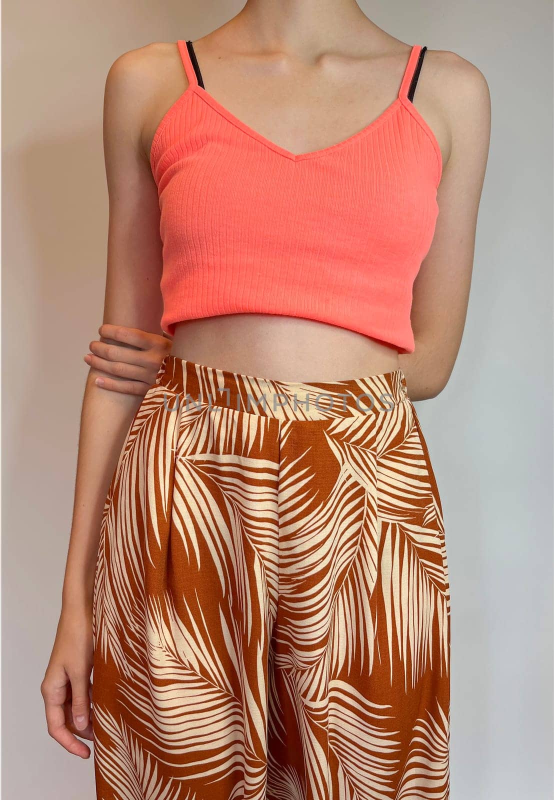 the body of a slender girl in a bright top with a bare stomach