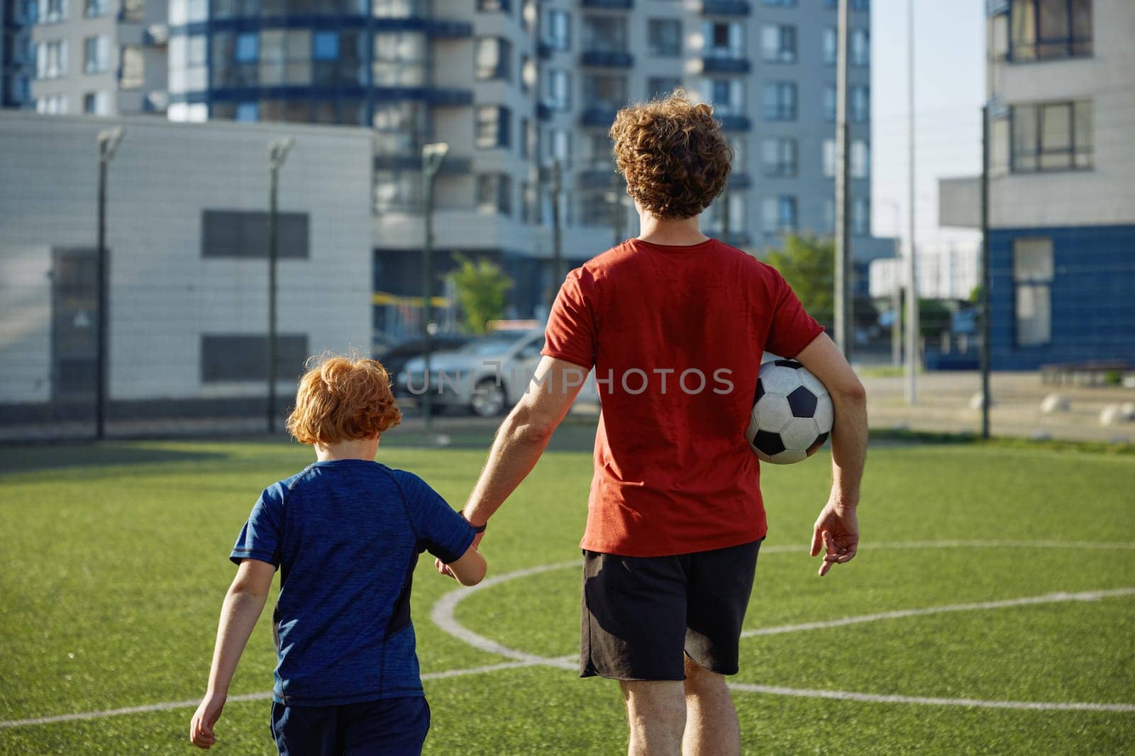 Father and son child walking on football field after successful game. Family sport recreation activity concept